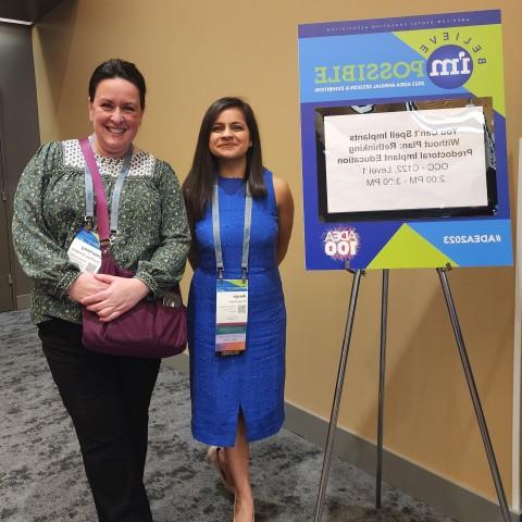 A student and faculty member pose in front of a research poster